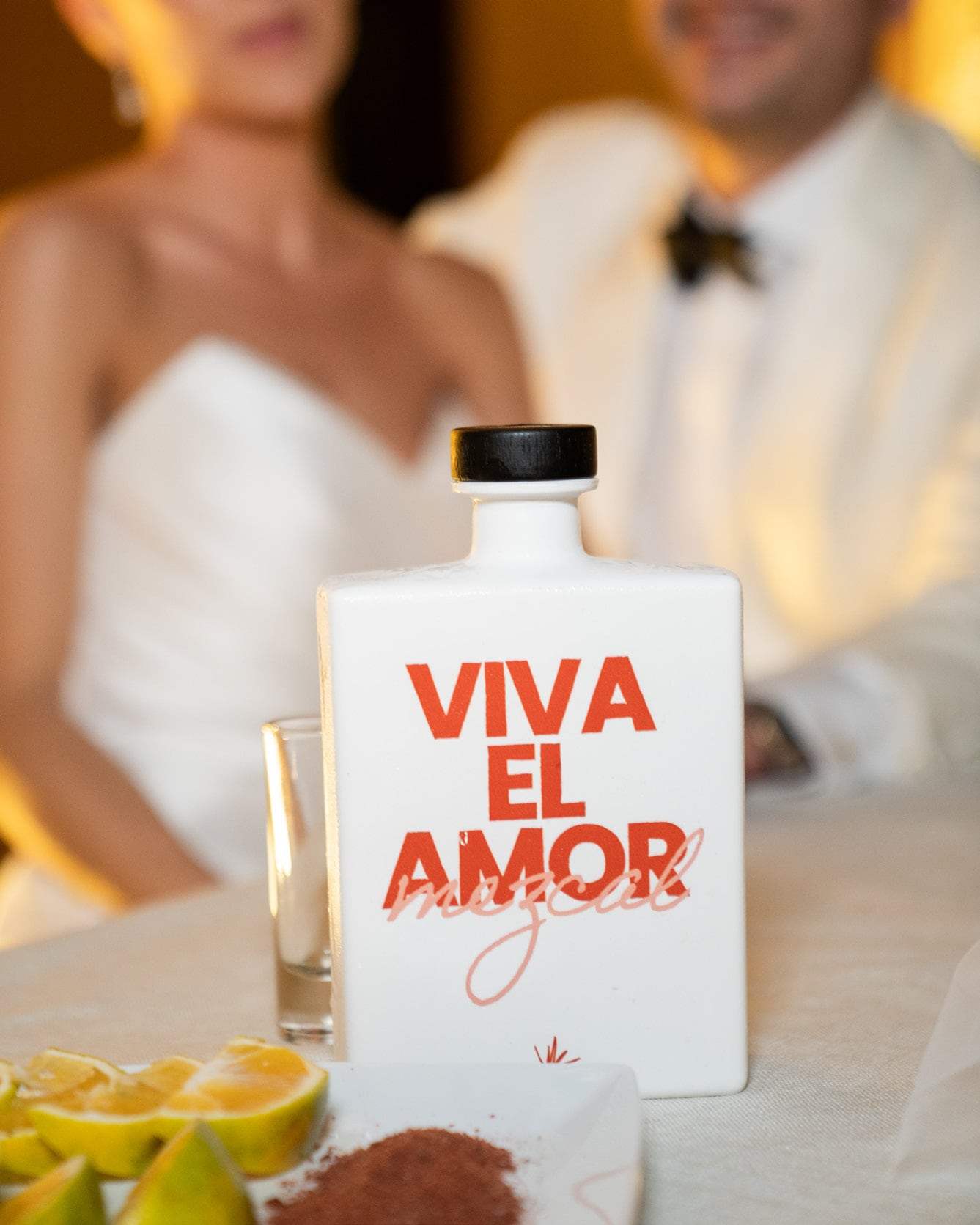 Los novios brindando con una botella Viva el amor durante la fiesta