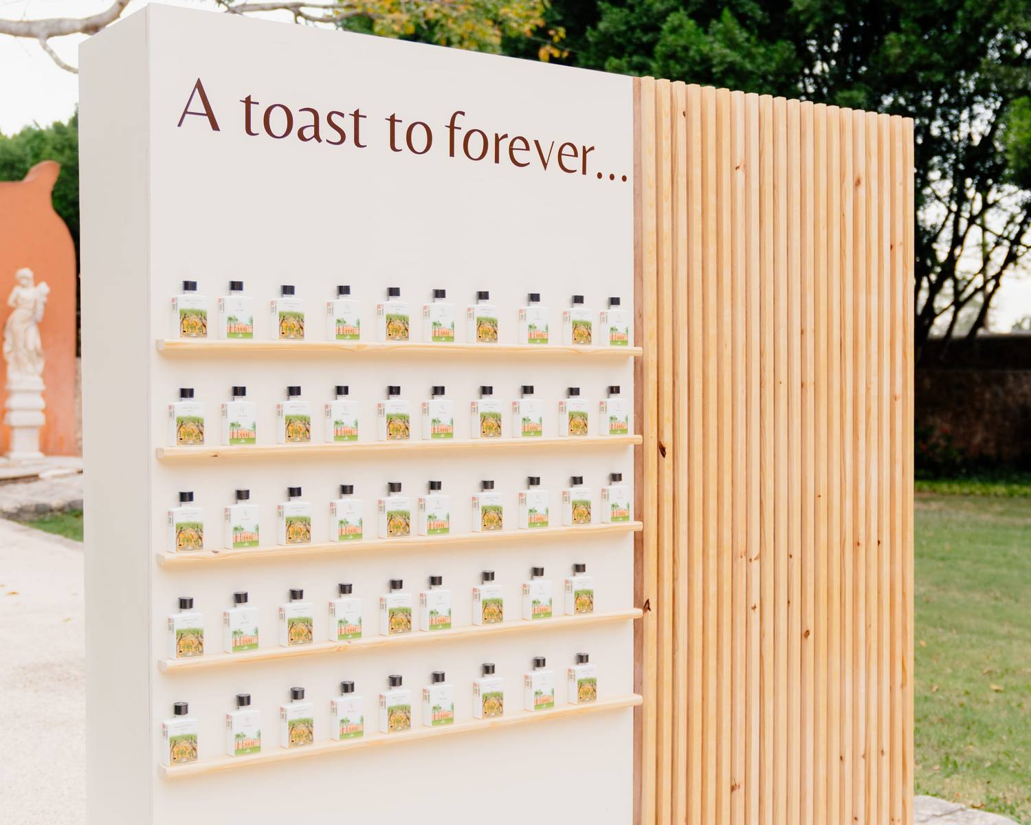 Muro de botellas personalizadas con el mensaje A toast to forever en una boda