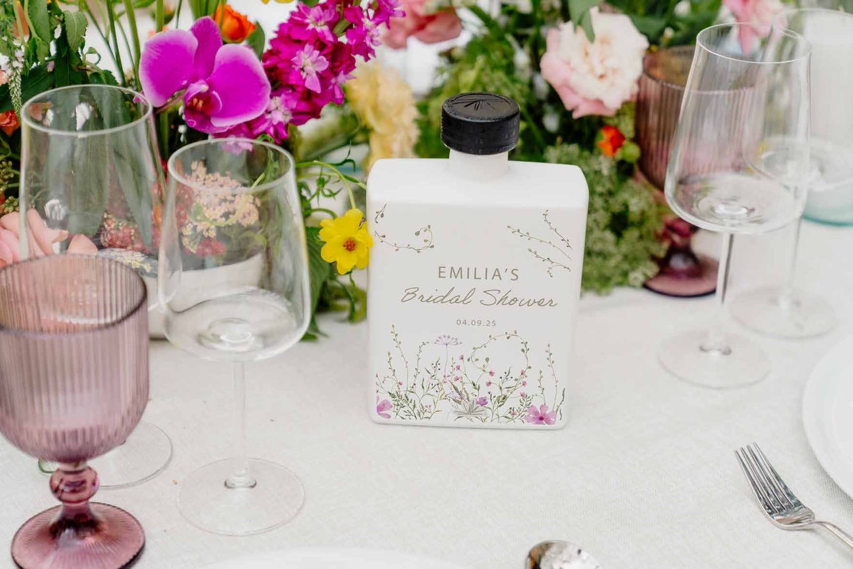 Botella personalizada para el bridal shower de Emilia junto a flores y copas