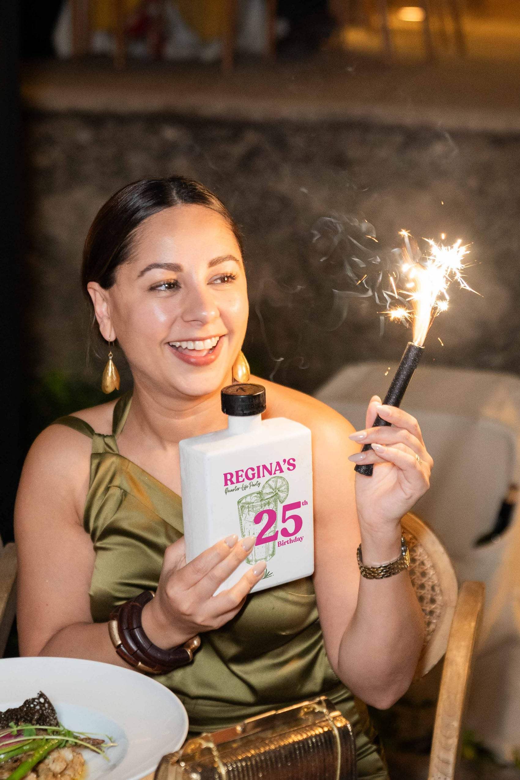 Invitada sosteniendo una botella personalizada de 25 años con una bengala encendida