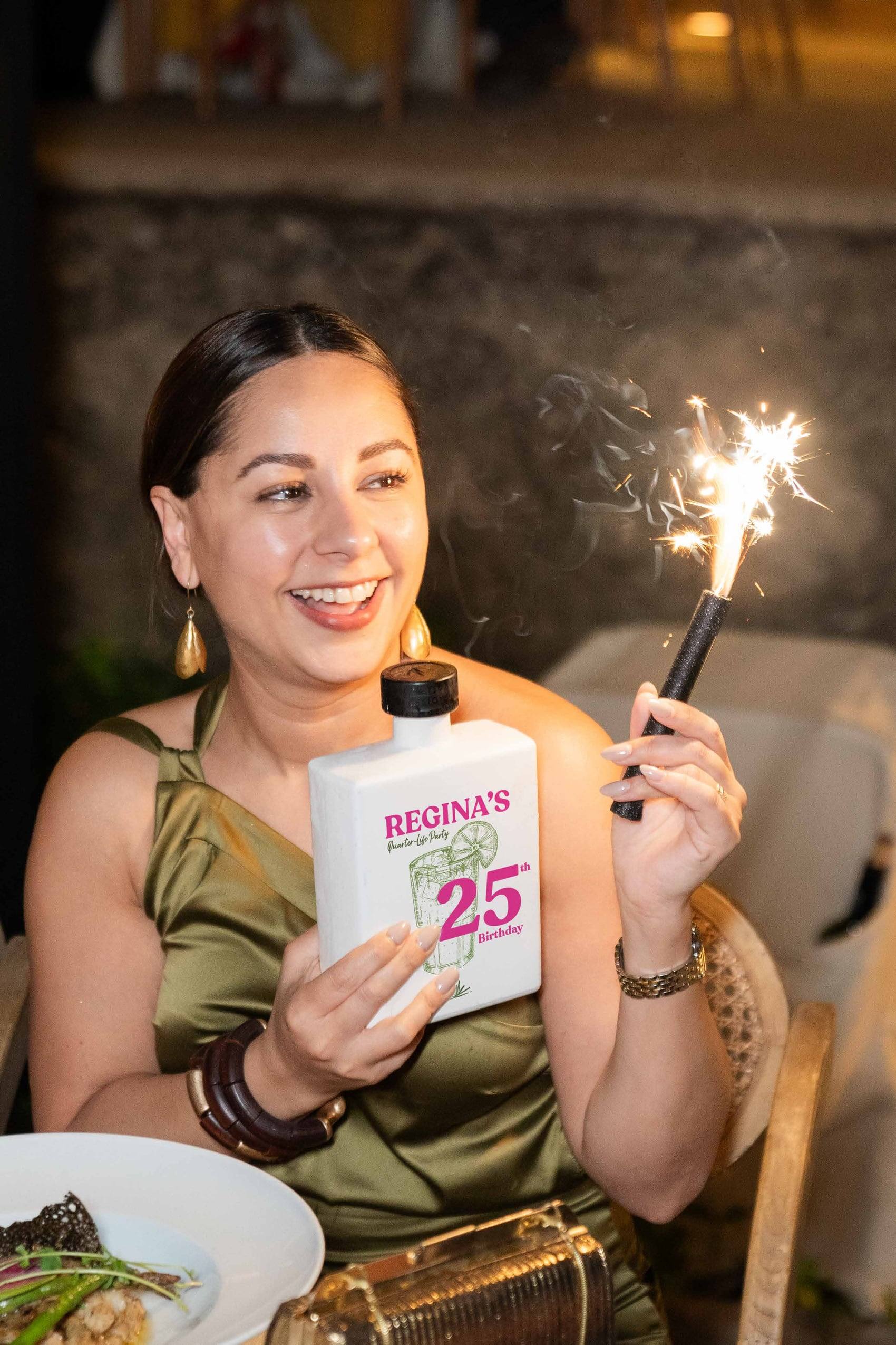 Invitada sosteniendo una botella personalizada de 25 años con una bengala encendida
