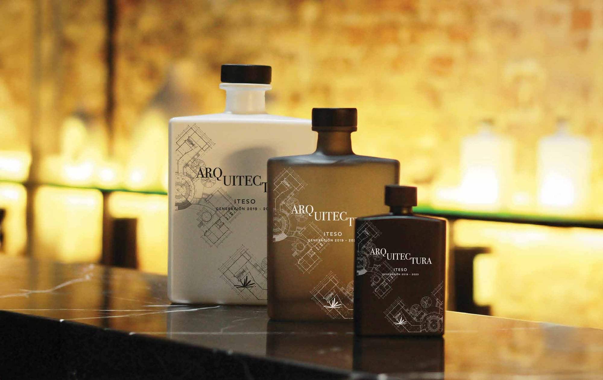 Tres botellas Master personalizadas para una graduación de arquitectura sobre una barra con velas