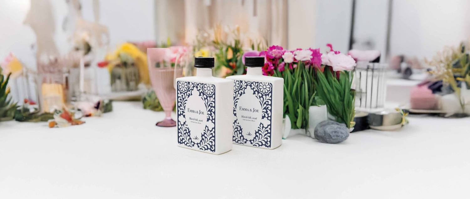 Dos botellas personalizadas Emma & Joe sobre una mesa con flores