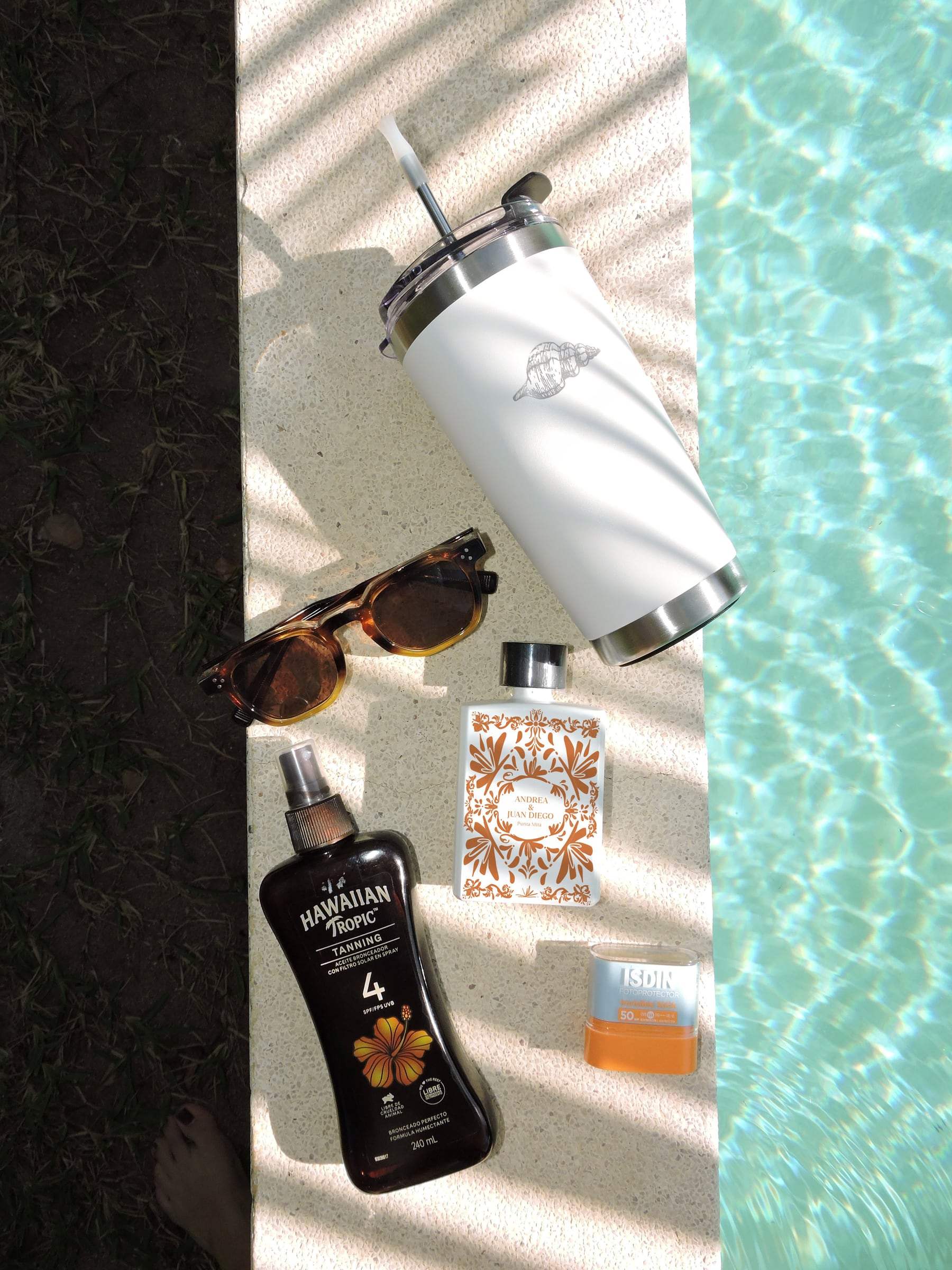 Botella Pocket personalizada junto a bloqueador y lentes de sol a la orilla de la alberca